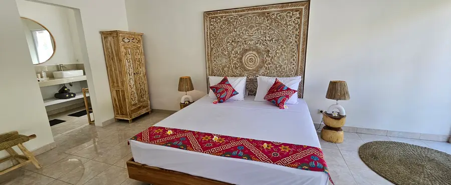 Chambre avec grand lit et tête de lit en bois sculpté