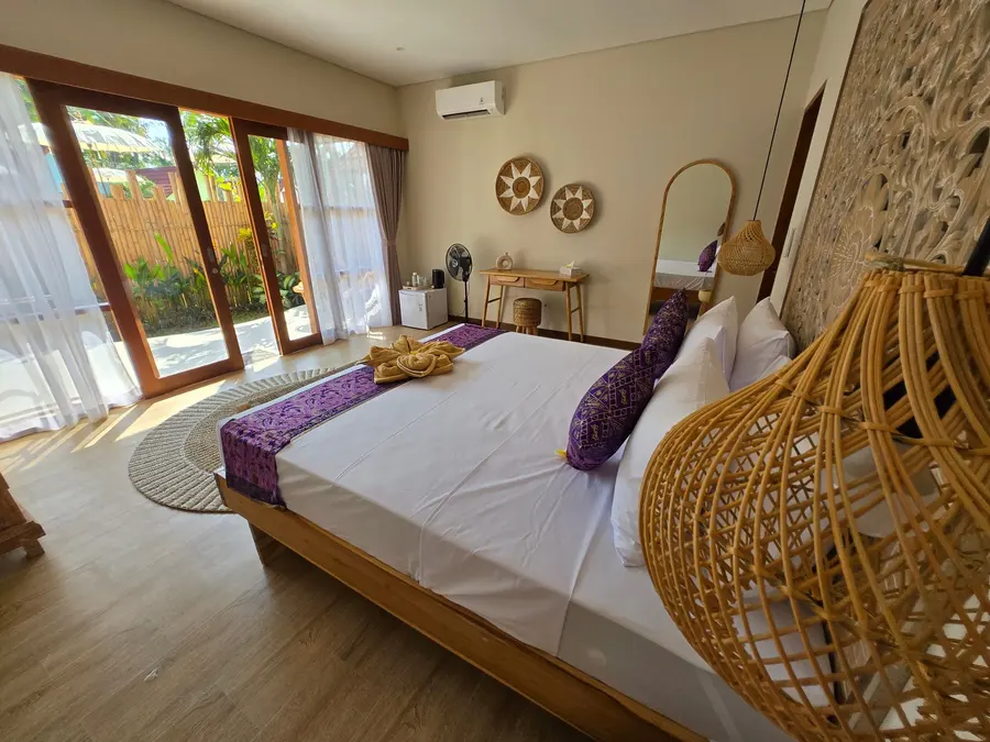 Chambre avec lit double, tête de lit en bois sculpté et vue sur la terrasse